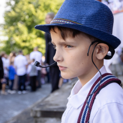 Puisis ar mikrofonu skatās tālumā.