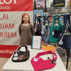 Meitene pie sava stenda tirdziņā.