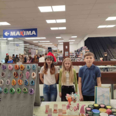 Trīs jaunieši pie sava stenda tirdziņā.