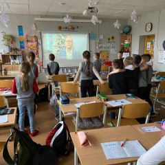 Bērmi klasē stāv kājās, seko ekrānā redzamajām aktivitātēm.