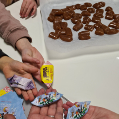Bērniem rokās pašu ietītas konfektes.