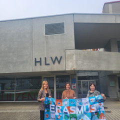 Skolotājas ar Erasmus+ karogu pie skolas.