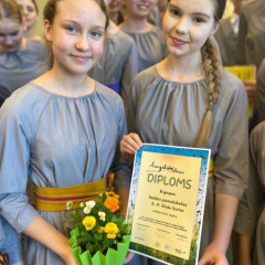 Kora meitenes tur rokās iegūto diplomu par augstāko pakāpi.