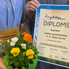 Kora meitenes tur rokās iegūto diplomu par augstāko pakāpi.