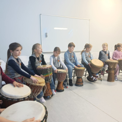 Bērni pusaplī sēž pie bungām.