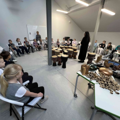 Mūzikas nodarbībā - kopskats - telpa ar bērniem un mūzikas instrumentiem.