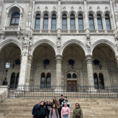 Projekta komanda pie Ungārijas parlamenta ēkas Budapeštā