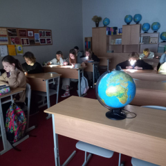 Bērni klasē lasa, uz galda globuss.