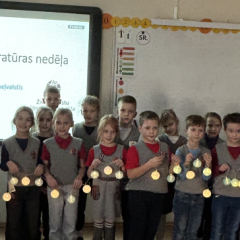 Bērmi klasē ar lampiņām rokās.