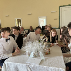 Zvana svētku pasākuma laikā skolēni pie sēž pie galda.